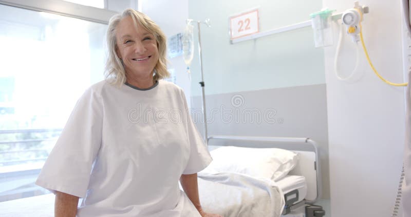 Portrait d'une patiente âgée caucasienne heureuse avec prothèse à la jambe assise dans le lit à l'hôpital