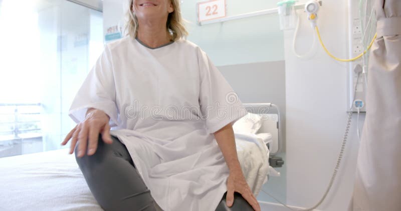 Portrait d'une patiente âgée caucasienne heureuse avec prothèse à la jambe assise dans le lit à l'hôpital