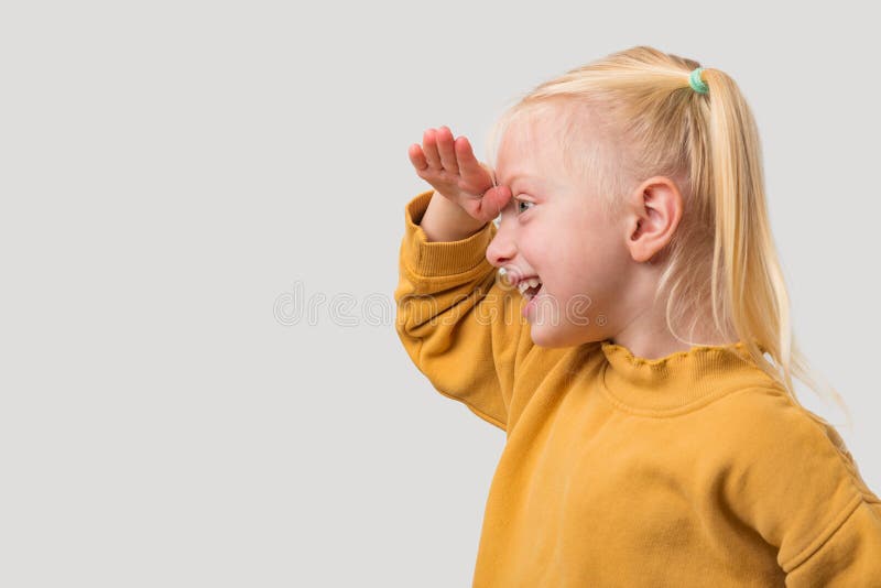 Portrait d'une petite fille aux cheveux blonds dans un chandail jaune regardant l'espace de copie isolé sur fond gris photographie stock libre de droits