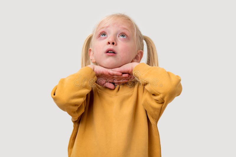 Portrait d'une petite fille aux cheveux blonds en chandail jaune qui regarde avec un visage surpris photos libres de droits