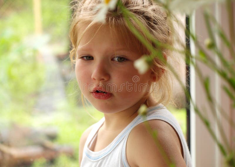 Portrait d'une petite fille avec les cheveux blonds jetant un coup d'oeil par derrière les tiges des marguerites photos stock Portrait d'une petite fille avec les cheveux blonds jetant un coup d'oeil par derrière les tiges des marguerites photos stock