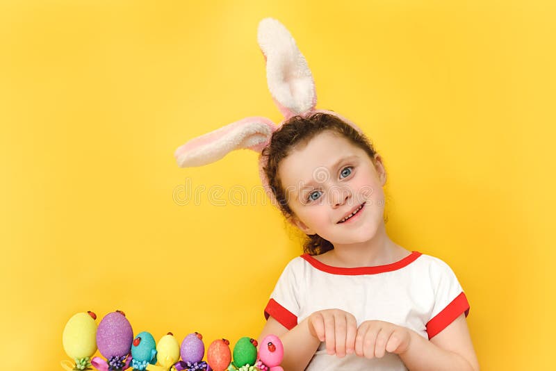 Portrait d'une petite fille drôle dans des oreilles de lapin moelleux positif regarder la caméra debout près de nombreux oeufs de photographie stock