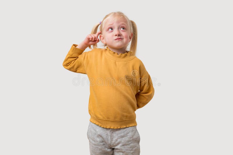 Portrait d'une petite fille mignonne aux cheveux blonds et aux yeux bleus portant un pull jaune image stock