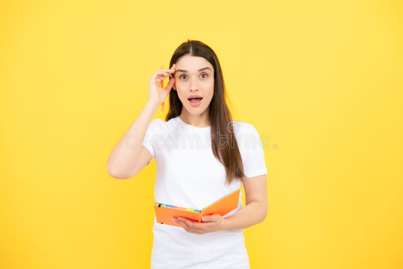 Portrait d'une étudiante. enseignement collégial ou secondaire. jeune femme sérieuse avec des cahiers à la caméra sur jaune