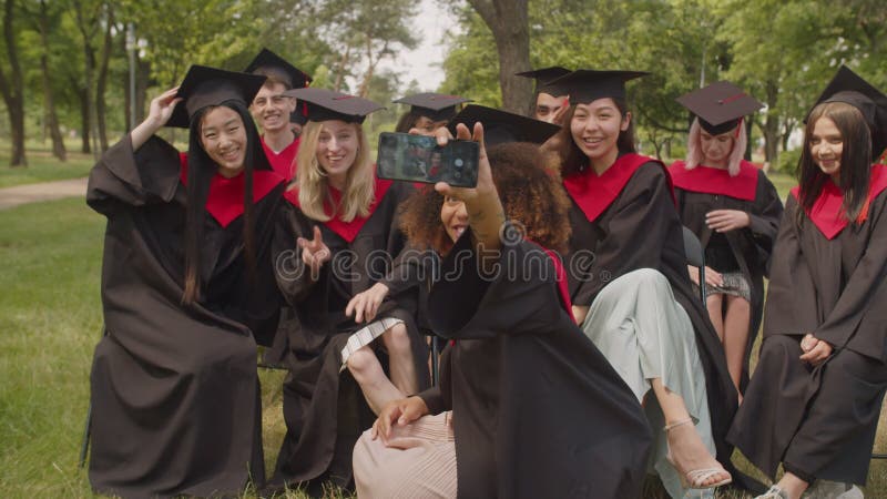 Portrait d'élèves insouciants en robe de fin d'études faisant le selfie au jour de la remise des diplômes clips vidéos