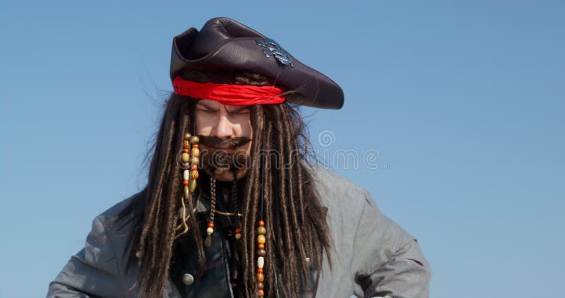 Portrait of dashing pirate who points at something and rubs his hands contentedly. Young man in a wig and pirate costume