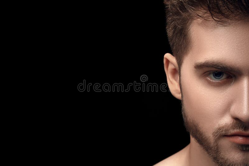 Portrait de beau jeune homme avec des yeux bleus sur le fond noir foncé Demi portrait de visage de l'homme avec la barbe Moitié a image stock Portrait de beau jeune homme avec des yeux bleus sur le fond noir foncé Demi portrait de visage de l'homme avec la barbe Moitié a image stock