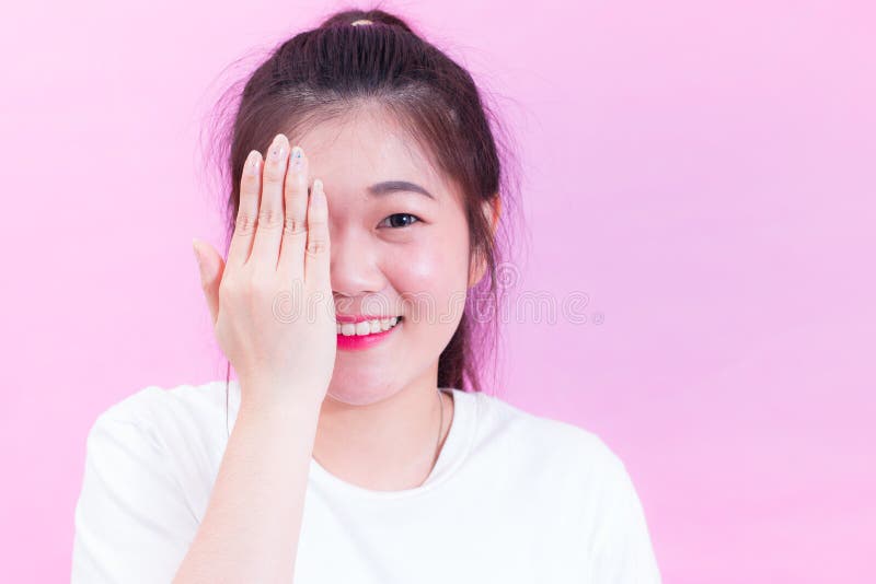 Portrait de beau jeune usage asiatique de cheveux noirs de femme une bâche blanche de T-shirt avec des mains son oeil et sourire images stock Portrait de beau jeune usage asiatique de cheveux noirs de femme une bâche blanche de T-shirt avec des mains son oeil et sourire images stock