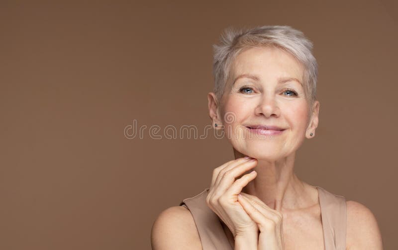 Portrait de beauté d'une femme mature souriant à la main sur le visage. visage closeup de femme âgée heureuse se sentant frais après traitement antiâge. beauté souriante regarder la caméra avec une peau parfaite.