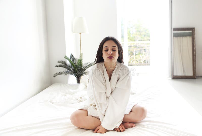 Portrait de belle femme dans le peignoir blanc dans la chambre à coucher photographie stock Portrait de belle femme dans le peignoir blanc dans la chambre à coucher photographie stock