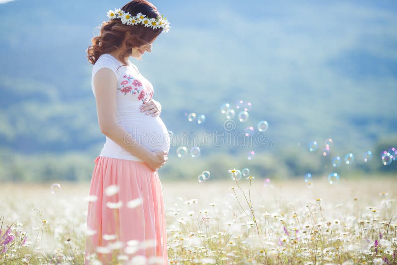 Portrait de belle femme enceinte dans les bulles de soufflement de champ photo stock Portrait de belle femme enceinte dans les bulles de soufflement de champ photo stock