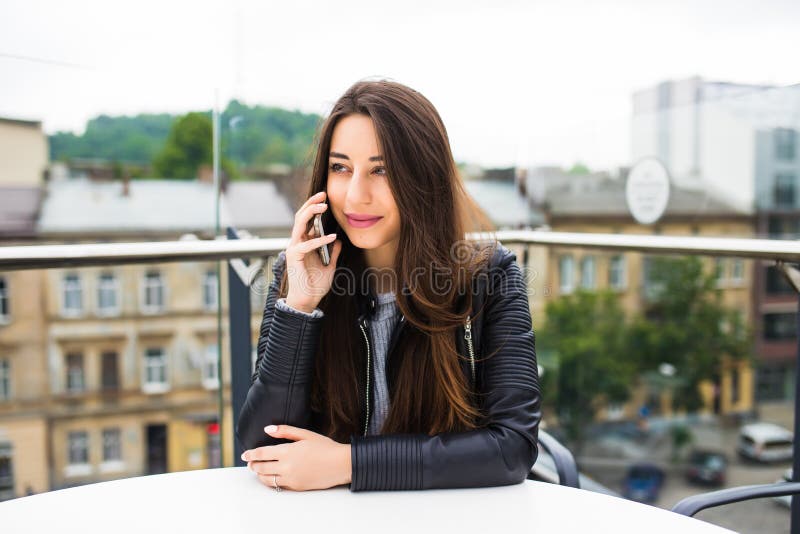 Portrait of beautiful young woman in coffee shop terrace, relaxing using smart phone, phone call conversation outdoors. Portrait of beautiful young woman in coffee shop terrace, relaxing using smart phone, phone call conversation outdoors.