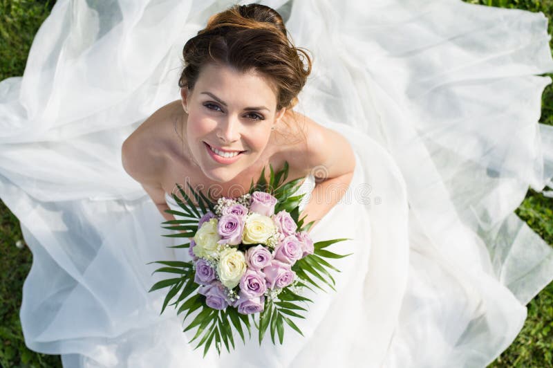 High View Portrait Of Beautiful Happy Bride Sitting On The Grass. High View Portrait Of Beautiful Happy Bride Sitting On The Grass