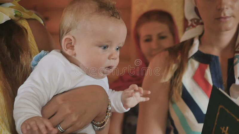 Portrait de bébé mignon dans des mains de marraine pendant le rituel de baptême