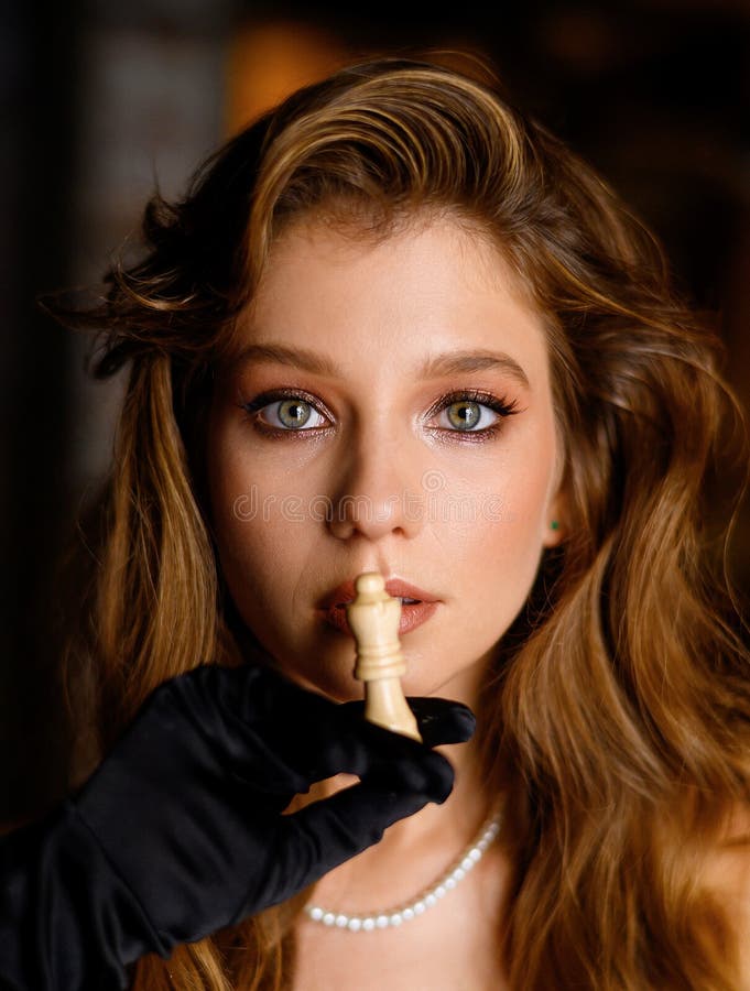 Portrait de closeup une belle fille caucasienne pose avec une pièce d'échecs. Une belle fille caucasienne en robe noire pose avec une pièce d'échecs. mode