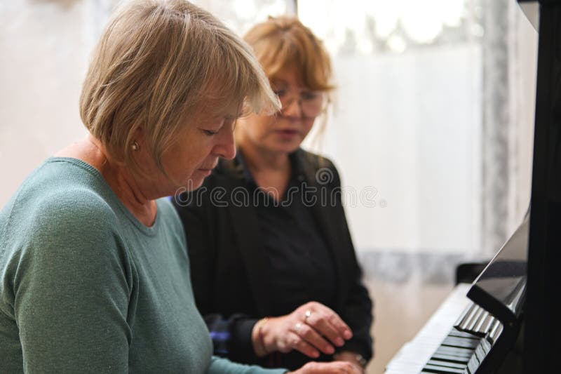 Portrait de deux femmes matures jouant du piano ensemble à la maison. musique comme thérapie. photographie stock libre de droits