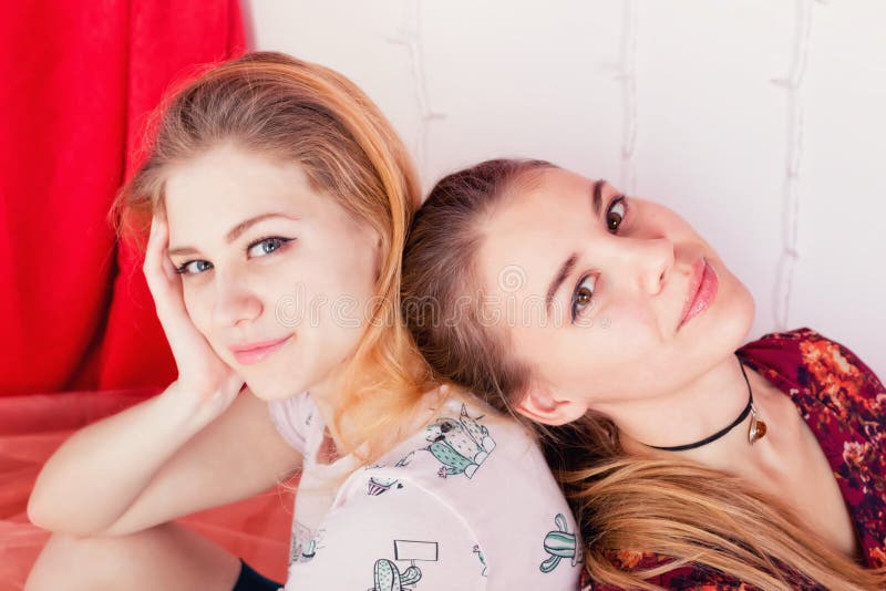 Portrait de deux jolies filles s'asseyant dans une pose de nouveau au dos photos libres de droits