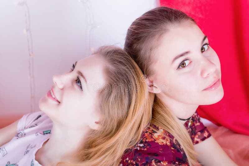 Portrait de deux jolies filles s'asseyant dans une pose de nouveau au dos photo libre de droits
