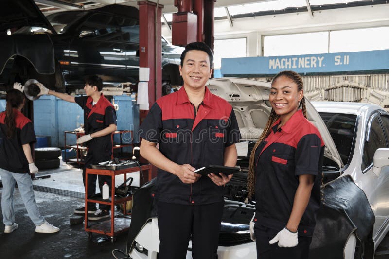 Portrait de deux ouvriers de mécaniciens professionnels heureux au garage de service de voiture. image stock
