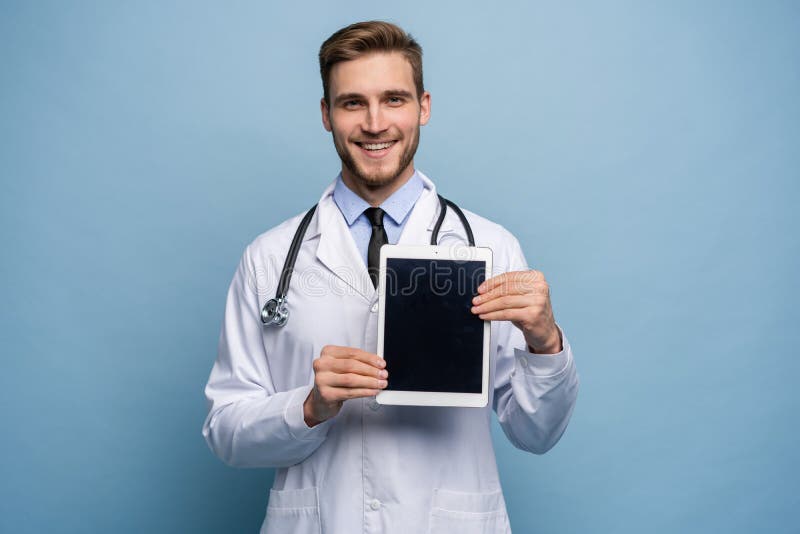 Portrait of friendly doctor presenting empty digital tablet screen. Isolated on light blue. Portrait of friendly doctor presenting empty digital tablet screen. Isolated on light blue