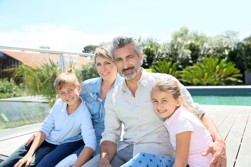 Portrait de famille heureuse devant la piscine photos stock Portrait de famille heureuse devant la piscine photos stock
