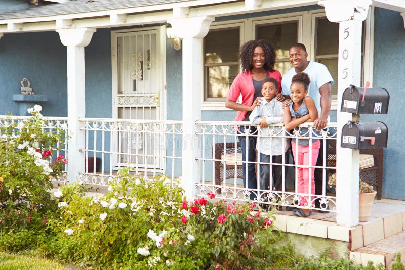 Portrait de famille se tenant sur le porche de la maison suburbaine photos libres de droits Portrait de famille se tenant sur le porche de la maison suburbaine photos libres de droits