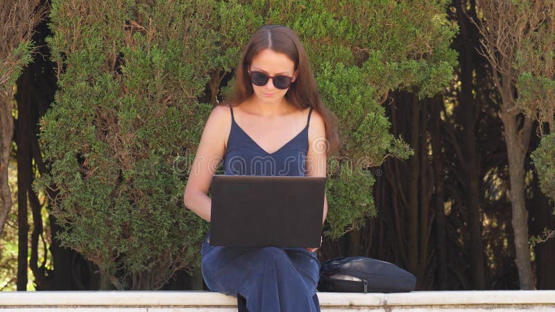 Portrait de femme d'affaires avec le fonctionnement de l'ordinateur portable au parc