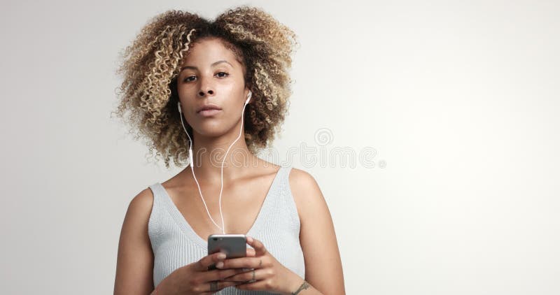 Portrait de femme de métis de beauté avec les cheveux et les taches de rousseur Afro avec les écouteurs et le smartphone clips vidéos