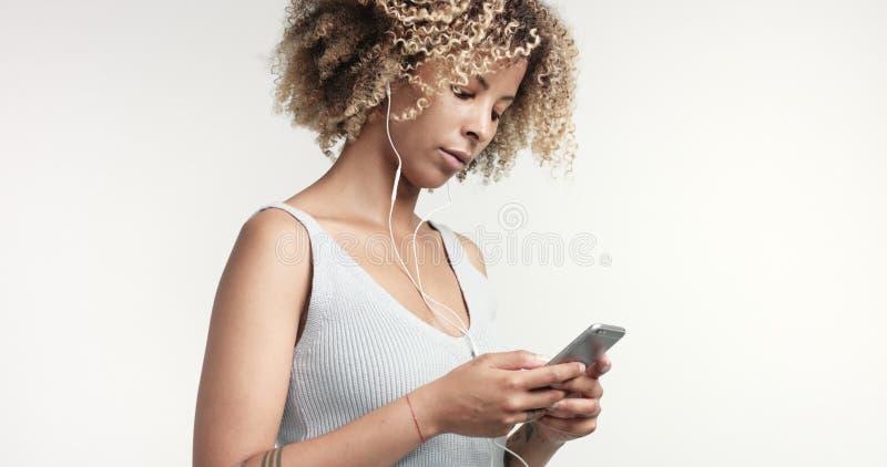 Portrait de femme de métis de beauté avec les cheveux et les taches de rousseur Afro avec les écouteurs et le smartphone banque de vidéos