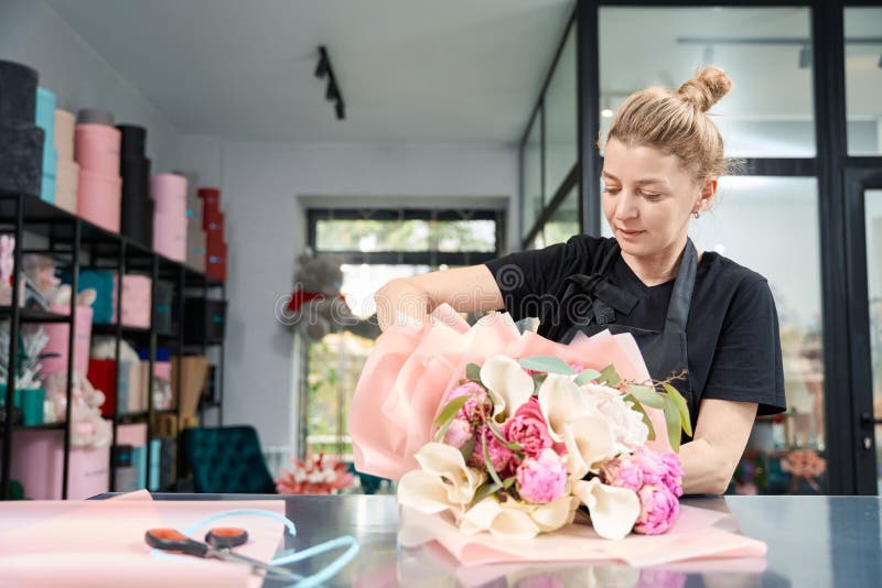 Portrait de femme en tablier tout en créant un bouquet élégant image stock