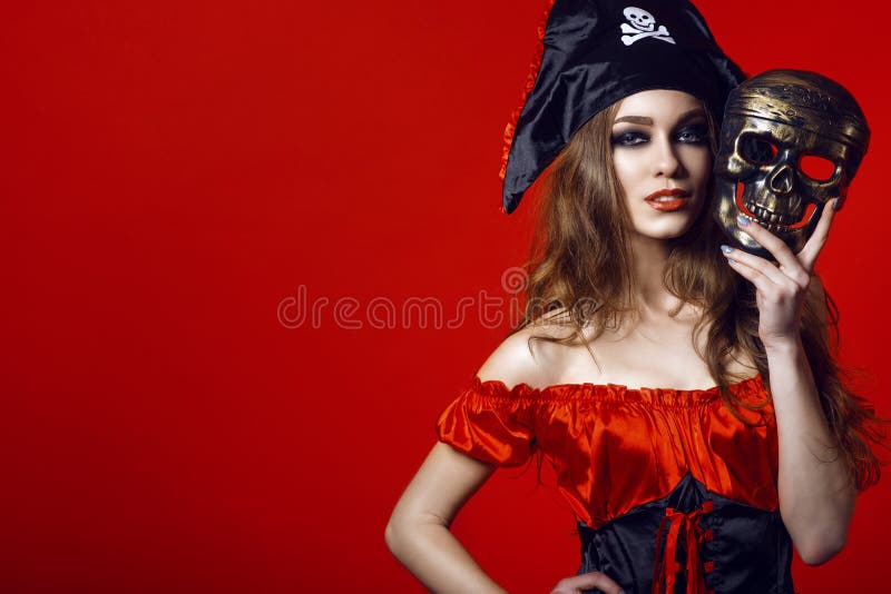 Portrait de femme sexy magnifique avec le maquillage provocateur dans le costume de pirate tenant le masque de crâne à côté de so image libre de droits Portrait de femme sexy magnifique avec le maquillage provocateur dans le costume de pirate tenant le masque de crâne à côté de so image libre de droits