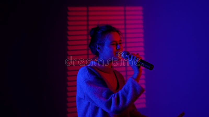 Portrait de femme silhouette chantant dans le microphone karaoké debout dans l'éclairage isolé sur le studio du néon bleu rouge banque de vidéos