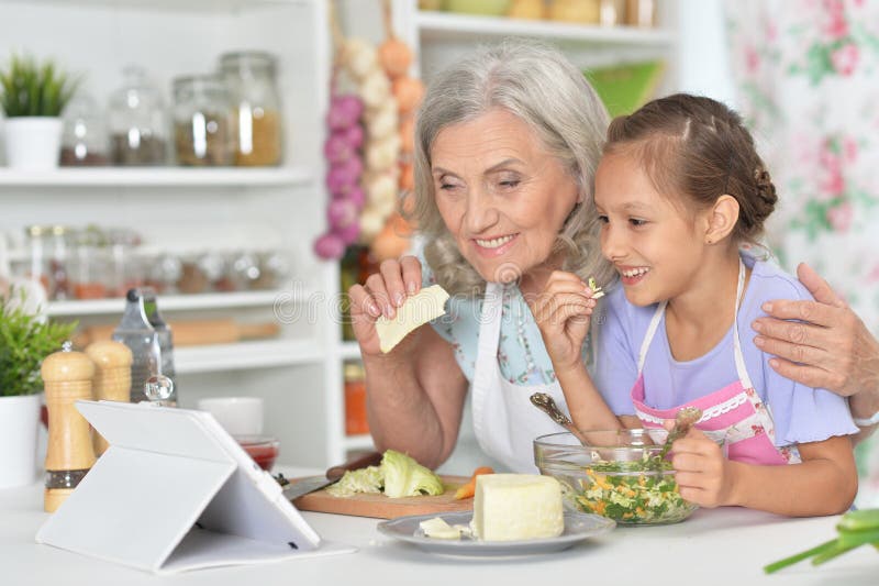 Portrait de femme supérieure avec la petite-fille préparant le dîner photo stock Portrait de femme supérieure avec la petite-fille préparant le dîner photo stock