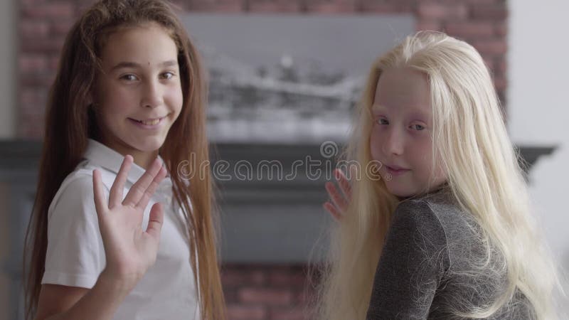 Portrait de fille de brune et de fille albinos avec les mains de ondulation de longs cheveux regardant le sourire de caméra Conce