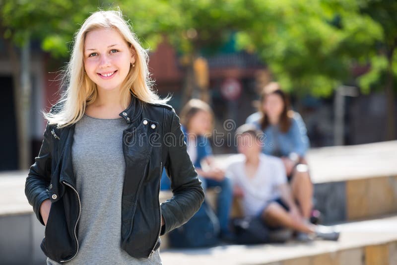 Portrait de fille d'adolescent se tenant hormis des amis dehors photographie stock Portrait de fille d'adolescent se tenant hormis des amis dehors photographie stock
