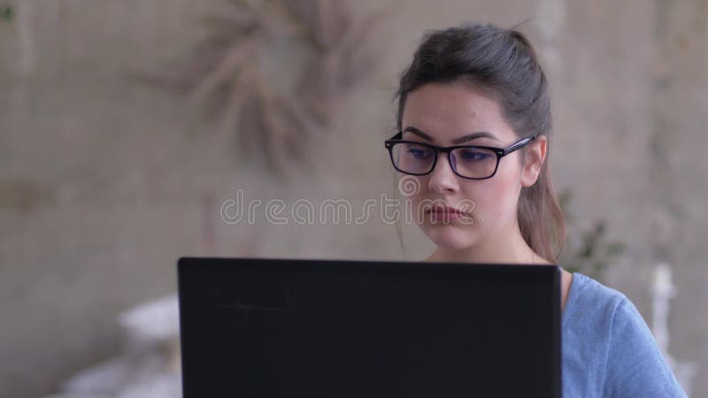 Portrait de fille d'indépendant dans le fonctionnement en verre sur l'ordinateur portable reposant en ligne à la maison en gros