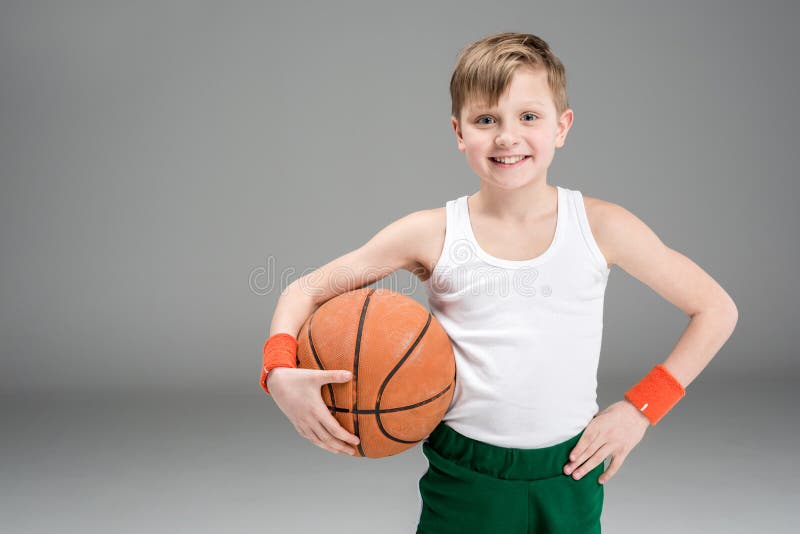 Portrait de garçon actif de sourire dans les vêtements de sport avec la boule de basket-ball images stock Portrait de garçon actif de sourire dans les vêtements de sport avec la boule de basket-ball images stock