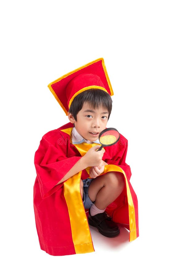 Portrait de garçon curieux dans l'obtention du diplôme rouge d'enfant de robe avec Mortarbo photo stock Portrait de garçon curieux dans l'obtention du diplôme rouge d'enfant de robe avec Mortarbo photo stock