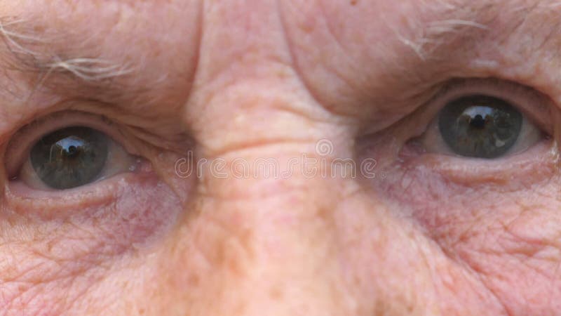 Portrait de grand-mère regardant dans la caméra avec un triste regard. gros yeux gris de femme âgée avec des rides autour clips vidéos