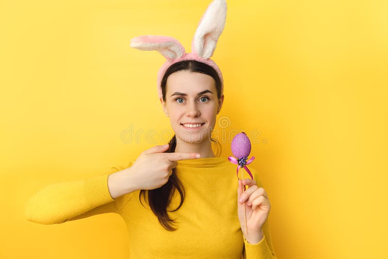 Portrait de jeune brune belle jeune femme souriante porte des oreilles de lapin moelleux pointant sur de petits oeufs colorés port image libre de droits