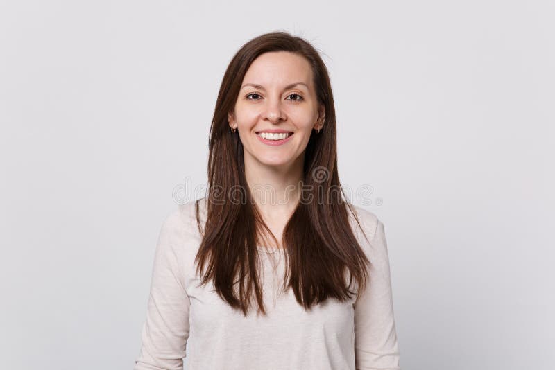 Portrait de jeune femme attirante de sourire dans des vêtements légers tenant et regardant la caméra d'isolement sur le fond blan photo stock Portrait de jeune femme attirante de sourire dans des vêtements légers tenant et regardant la caméra d'isolement sur le fond blan photo stock