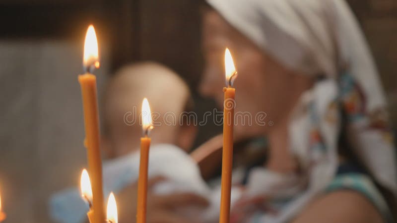 Portrait de jeune femme avec le petit garçon derrière les bougies dans l'église