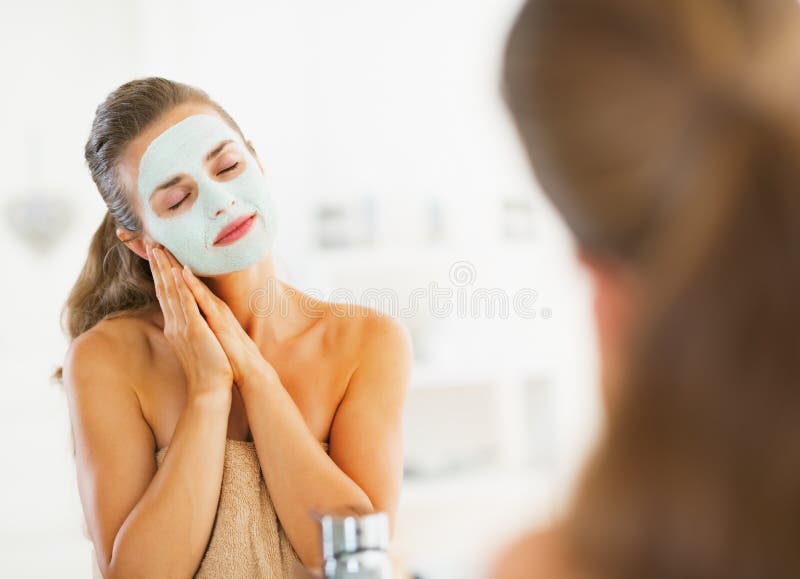Portrait of happy young woman with cosmetic mask on face in bathroom. Portrait of happy young woman with cosmetic mask on face in bathroom