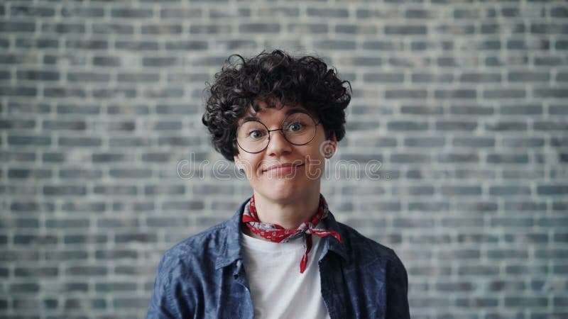 Portrait de jeune femme joyeuse faisant les visages drôles sur le fond de brique banque de vidéos