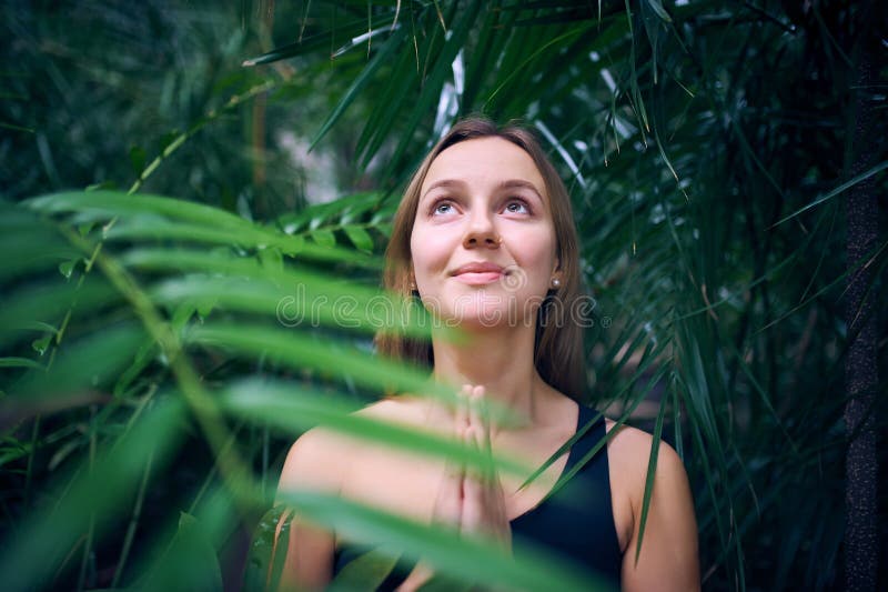 Portrait de jeune femme mignonne méditant et faisant la main de namaste dans la jungle Jour ensoleillé photographie stock Portrait de jeune femme mignonne méditant et faisant la main de namaste dans la jungle Jour ensoleillé photographie stock