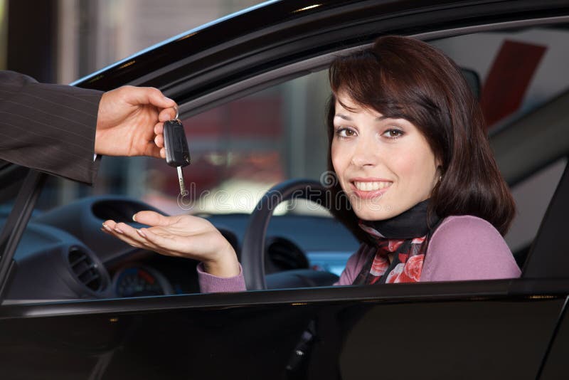 Portrait de jeune femme recevant les clés de voiture du vendeur de voiture image stock Portrait de jeune femme recevant les clés de voiture du vendeur de voiture image stock