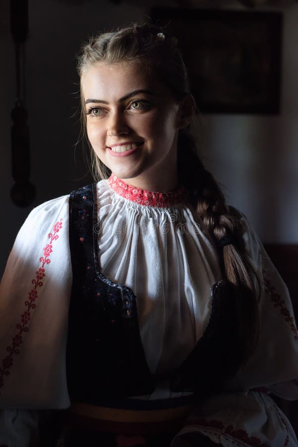 Portrait de jeune femme à l'intérieur de maison traditionnelle avec le costume traditionnel roumain photos libres de droits Portrait de jeune femme à l'intérieur de maison traditionnelle avec le costume traditionnel roumain photos libres de droits