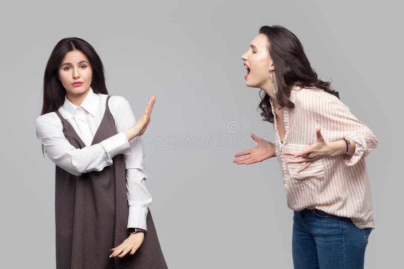 Portrait de jeune fille regardant la caméra et montrant l'arrêt ou ignorer à une autre fille qui criant à elle conflit entre deux images stock