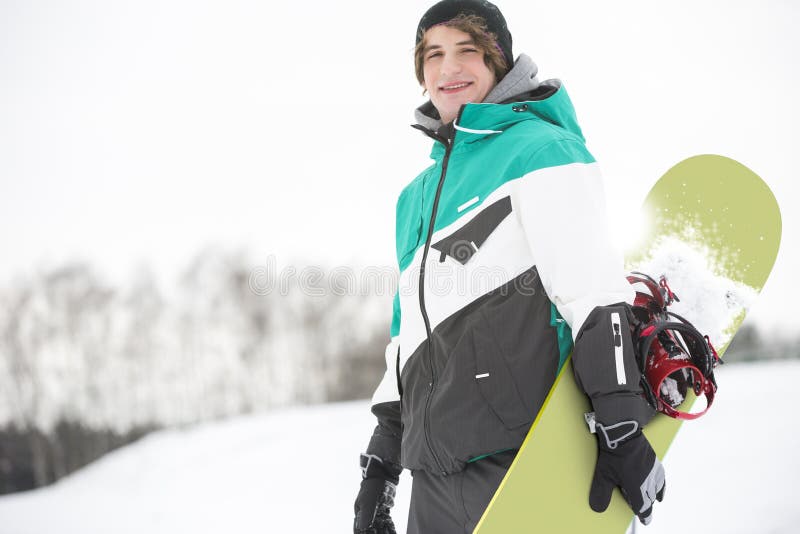 Portrait de jeune homme beau avec le surf des neiges dans la neige photos stock Portrait de jeune homme beau avec le surf des neiges dans la neige photos stock