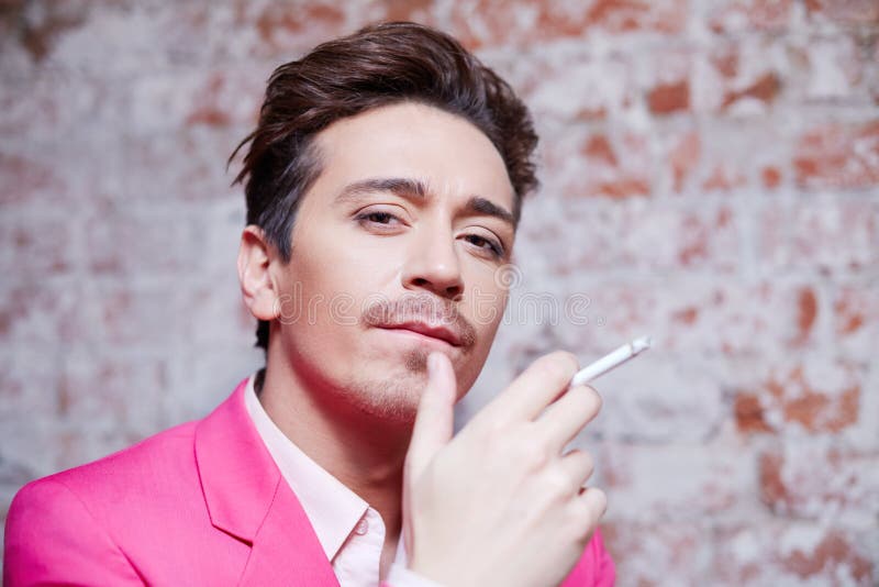Portrait de jeune homme dans le costume rose avec la cigarette photo libre de droits Portrait de jeune homme dans le costume rose avec la cigarette photo libre de droits